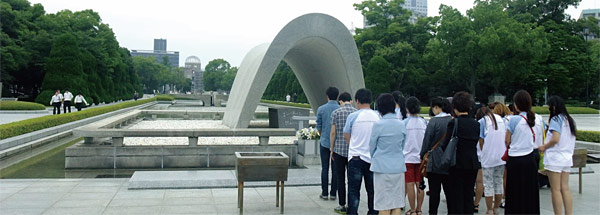 히로시마 평화기념공원을 방문한 새터민 대학생 19명이 원폭위령비 앞에서 묵념하고 있다. 위령비 뒤쪽으로 원폭피해의 상징인 ‘원폭돔’이 보인다.
