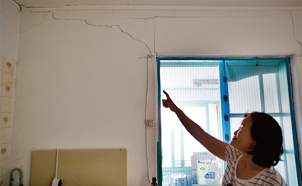 대성동 마을의 한 주민이 금이 간 자신의 집 벽을 가리키고 있다.