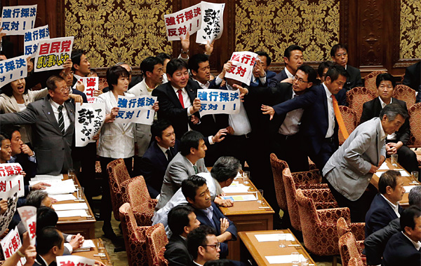 지난 7월 15일 열린 중의원 안보법제 특별위원회 회의실에서 안보법안에 반대하는 야당 의원들이 피켓을 들고 몸싸움을 벌이고 있다. ⓒphoto AP