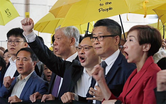 지난 11월 19일 홍콩 민주화운동을 주도한 찬킨만 홍콩중문대 교수, 베니 타이 홍콩대 교수 등이 홍콩 법원에 재판을 받으러 출석하며 민주화운동의 상징인 노란 우산을 들어보이고 있다. ⓒphoto AP
