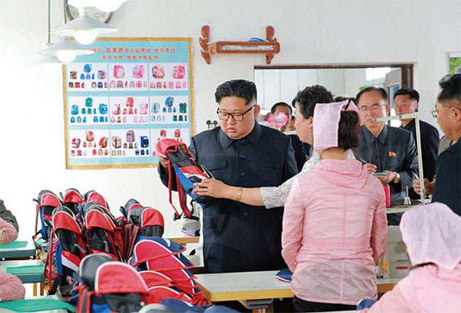 김정은이 청진의 가방 공장에서 학생용 가방을 살펴보고 있다. ⓒphoto 노동신문