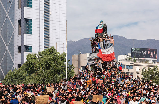 칠레 산티아고 시민들이 지난 10월 22일(현지시각) 바케다노 광장 중심부에 위치한 전쟁영웅 마누엘 바케다노 장군 동상에 올라가 정부에 항의하고 있다.