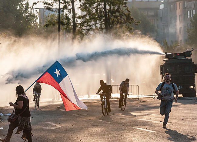 시위대들이 해질 무렵 바케다노 광장에서 물대포를 피해 도망가고 있다.