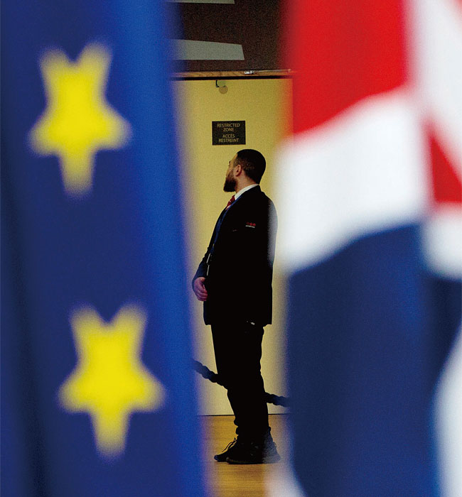 지난 1월 28일 화요일 브뤼셀의 유로파 빌딩에 있는 아트리움 안에 한 경비원이 유니온 국기와 EU 국기 사이에 서 있다. 영국은 2020년 1월 31일 금요일 EU를 탈퇴했다. ⓒphoto 뉴시스·AP