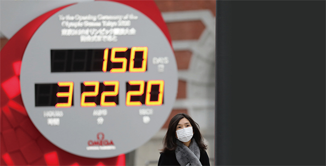 지난 2월 25일 올림픽 카운트다운을 표시한 도쿄 도심 전광판 아래를 마스크를 쓴 시민이 지나가고 있다. ⓒphoto 뉴시스