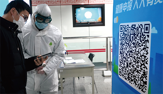 지난 2월 20일 중국 허난성 정저우의 한 지하철역에서 방호복을 입은 방역요원이 QR코드를 확인하고 있다. ⓒphoto 신화·뉴시스