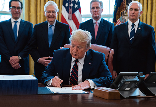 지난 3월 27일 트럼프 대통령이 백악관 오벌오피스에서 코로나19 대응 경기부양책에 서명하고 있다. ⓒphoto 뉴시스