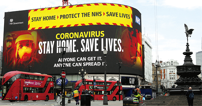 지난 4월 8일 영국 런던 피커딜리광장에 코로나19 대응 지침 현수막이 내걸려 있다. ‘집에 있자, NHS를 보호하자, 그리고 생명을 살리자’는 구호는 요즘 영국 곳곳에서 볼 수 있다. ⓒphoto 뉴시스