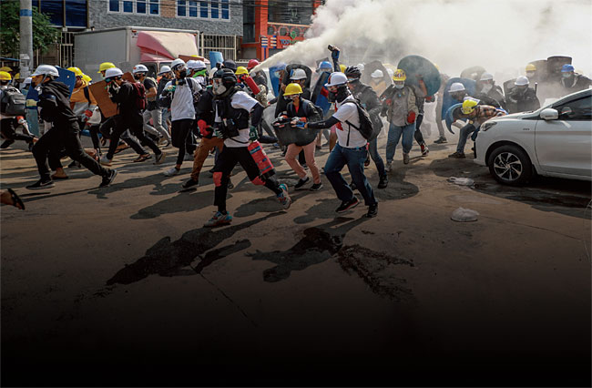 지난 3월 3일 미얀마 양곤에서 시위대들이 최루가스를 피해 도망가면서 경찰이 쏜 최루가스 효과를 떨어뜨리기 위해 소화기를 분무하고 있다. ⓒphoto 뉴시스