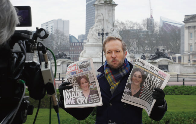 영국의 한 방송사 기자가 지난 3월 버킹엄궁 앞에서 메건 마클 왕세자비 폭로 사태를 다룬 신문을 들고 방송을 진행하고 있다. ⓒphoto 뉴시스