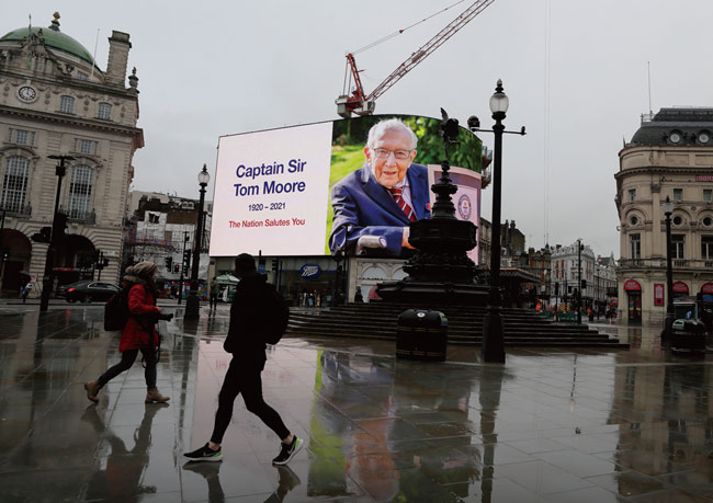 ‘캡틴 톰’으로 불렸던 영국의 자선사업가 토머스 무어 경을 추모하는 대형 사진이 런던 피커딜리광장에 내걸려 있다. 지난 2월 2일 세상을 뜬 토머스 무어 경은 지난해 99세의 나이에 코로나19와 싸우는 영국 국민보건서비스(NHS)를 위한 모금 캠페인을 벌여 영국을 감동시켰다. ⓒphoto 뉴시스