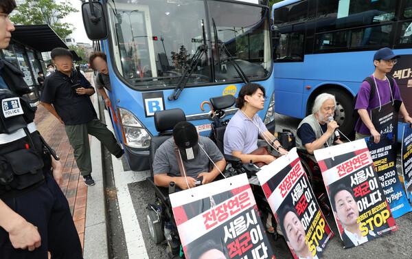 지난 13일 오전 서울 종로구 혜화동로터리에서 한 시민이 출근길 버스를 가로막은 박경석 전국장애인차별철폐연대 대표와 회원들에게 항의하고 있다. photo 뉴시스