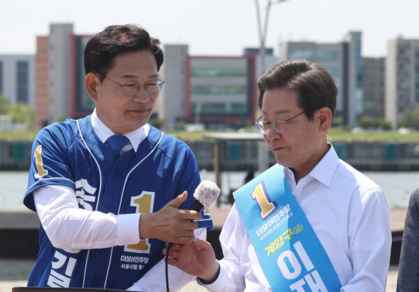 더불어민주당 서울시장 후보였던 송영길 전 대표가 2022년 5월 27일 김포시 고촌읍 아라 김포여객터미널 아라마린센터 앞 수변광장에서 열린 김포공항 이전 수도권 서부 대개발 정책협약 기자회견에서 이재명 인천 계양을 국회의원 후보에게 마이크를 넘기고 있다.<BR> photo 뉴시스