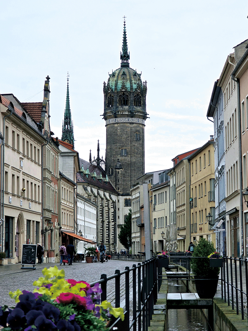 비텐베르크 골목길에서 보이는 성채교회. 둥근 첨탑 주위로 ‘Ein Feste Burg Ist Unser Gott(내 주는 강한 성이요)’라는 글자가 적혀 있다.