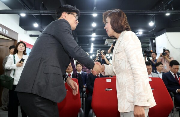 지난 7월 열린 국민의힘 전당대회 당시 당대표 후보였던 나경원 국민의힘 의원과 한동훈(왼쪽) 대표가 서울 여의도 국민의힘 중앙당사에서 열린 미래를 위한 약속, 공정 경선 서약식에서 악수하고 있다. photo 뉴시스