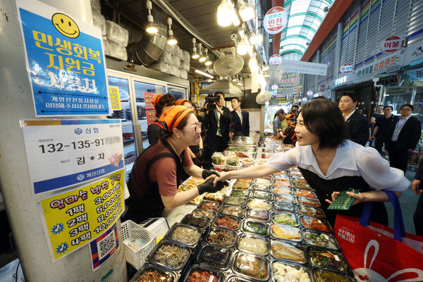 이재명 대통령의 부인 김혜경 여사(오른쪽)가 지난 7월 25일, 인천 계양산 전통시장을 찾아 민생회복 소비쿠폰을 이용해 음식을 구매한 뒤 상인과 인사하고 있다. photo 뉴시스