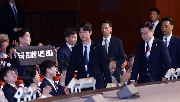 15일, 광복 80주년 기념식이 열린 서울 광화문 세종문화회관에서 안철수 국민의힘 당대표 후보(왼쪽)가 입장하는 이재명 대통령 앞에서 조국, 윤미향 사면에 반대하는 플래카드를 펼쳐 보이고 있다. photo 뉴시스