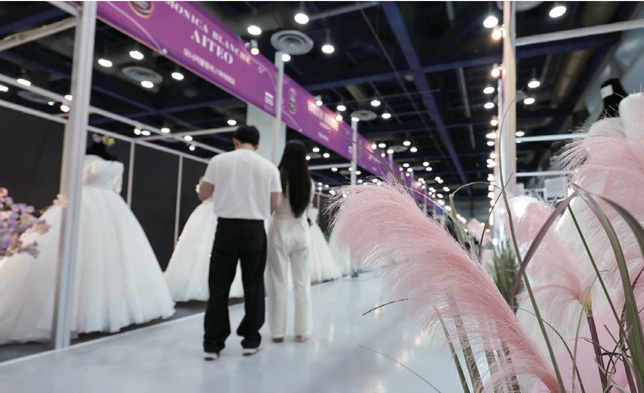 서울 강남구 삼성동 코엑스에서 열린 2025 추계 웨덱스 웨딩박람회에서 예비 부부들이 전시된 드레스를 살펴보고 있다. photo 뉴스1